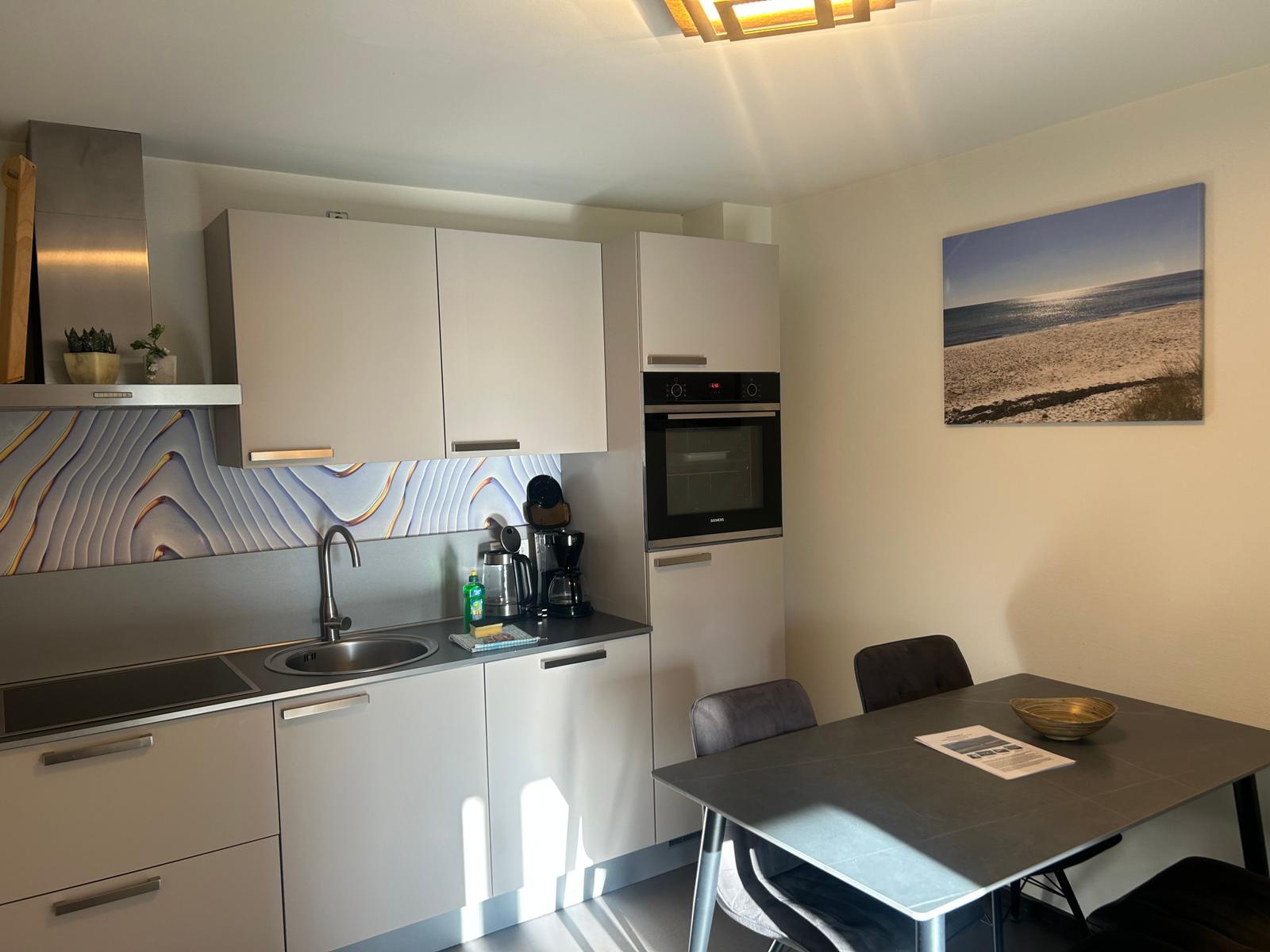 Küche mit Essbereich, modern eingerichtet mit Küchenschränken und Tisch.