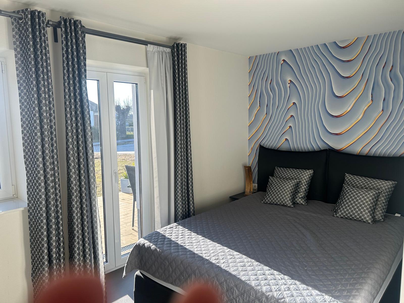 Schlafzimmer mit Bett, Fenster und Wanddekoration.