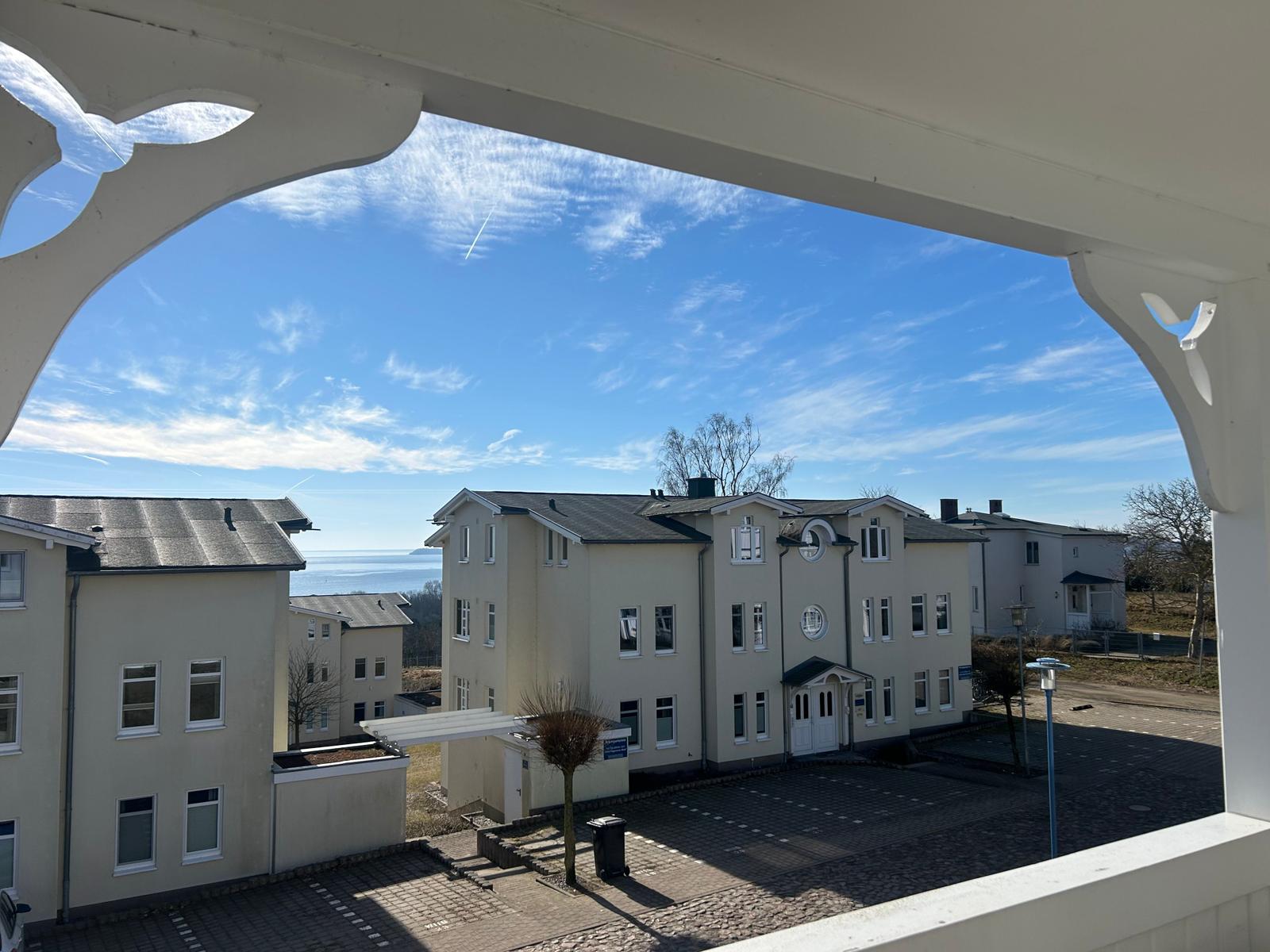 Weitblick vom Balkon auf Wohnhaus und Meer unter blauem Himmel.