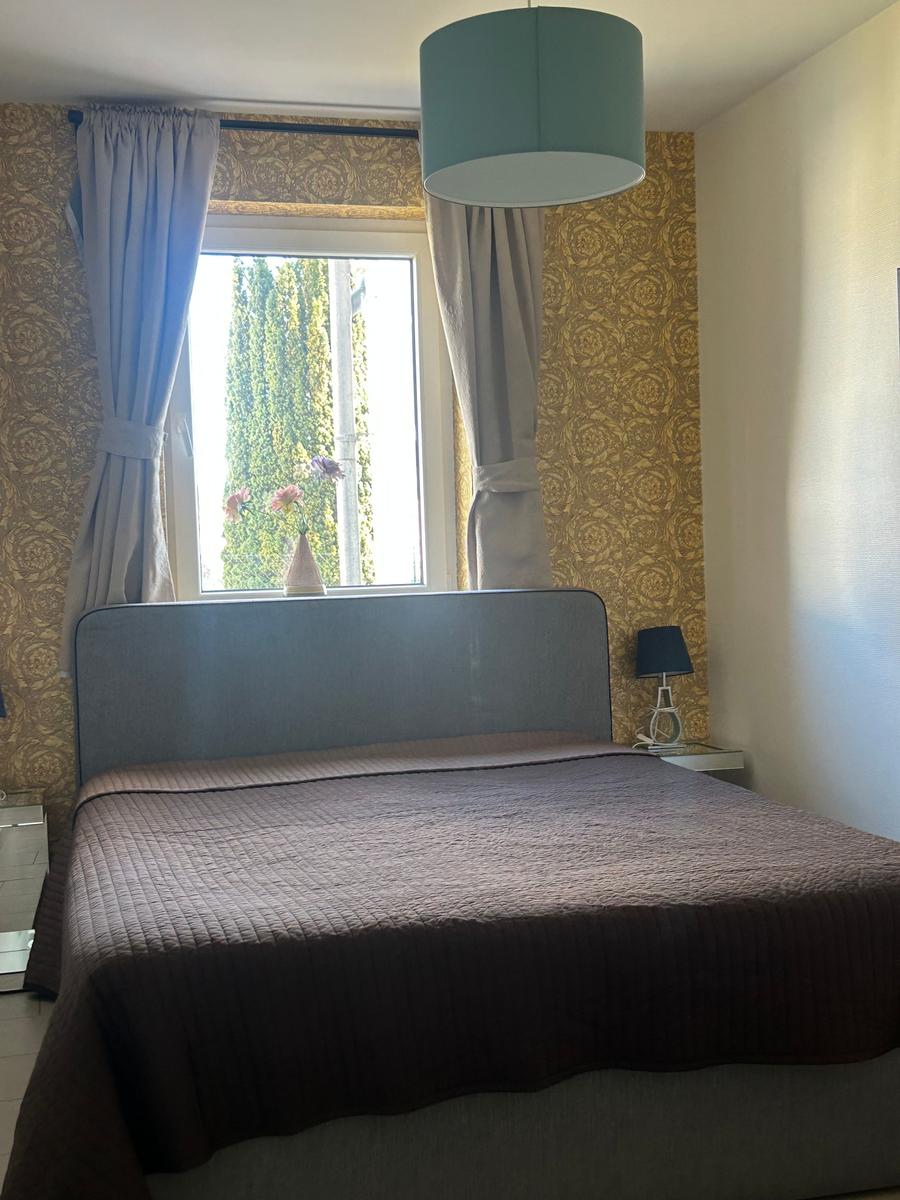 Schlafzimmer mit Bett, Fenster und Wandtapete.