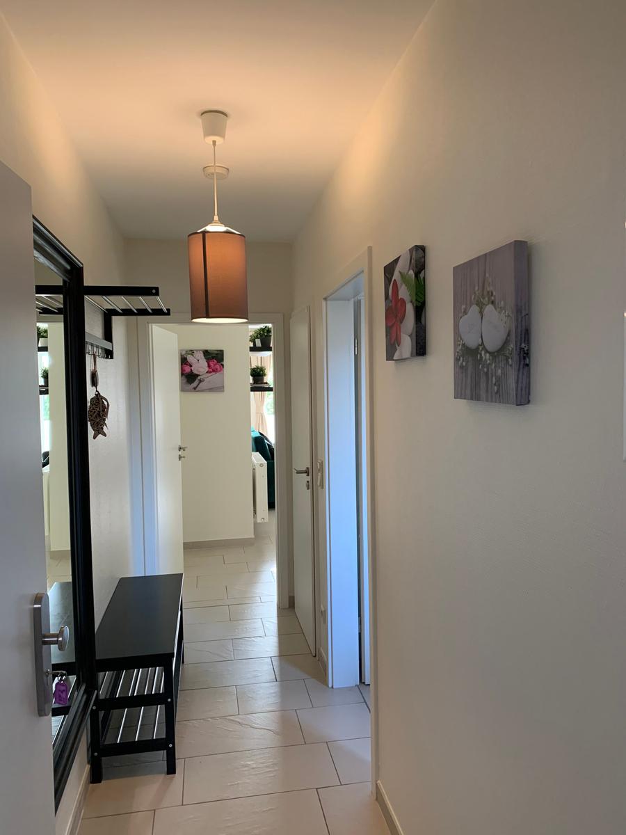 Flur mit Lampen, Bildern und Schuhschrank. Türen zu weiteren Räumen.