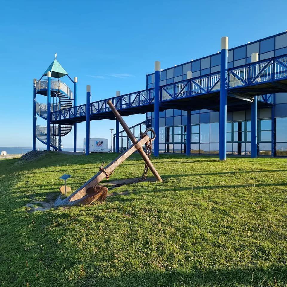 Großer blauer Spielplatz mit Turm und Anker im Gras.
