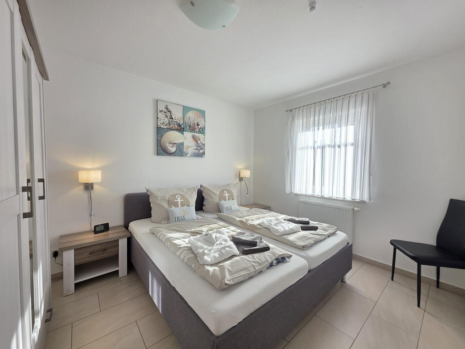 Bedroom with double bed, nightstand, window, and chair.