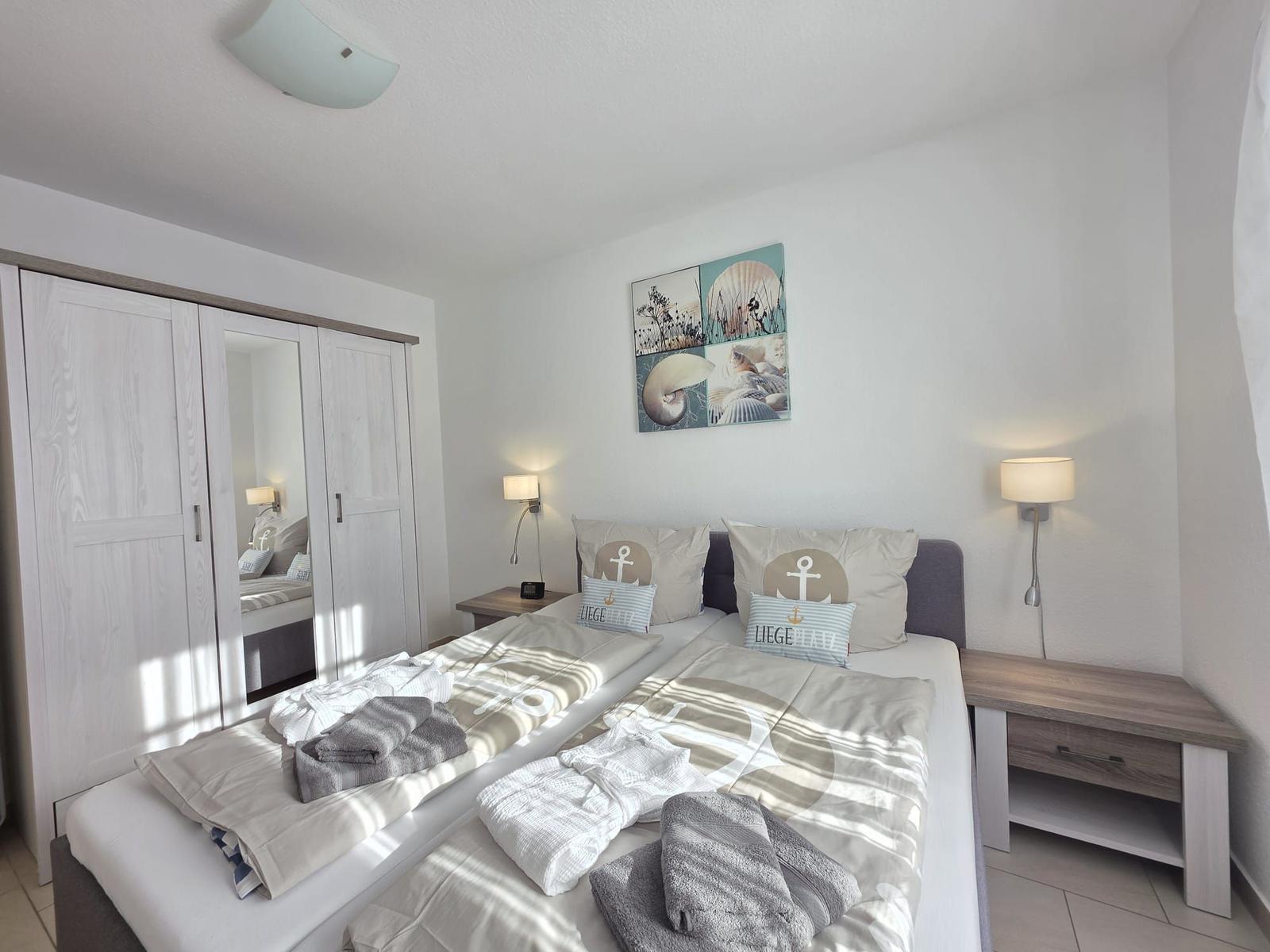 Bedroom with double bed, wardrobe, and wall art with shells.