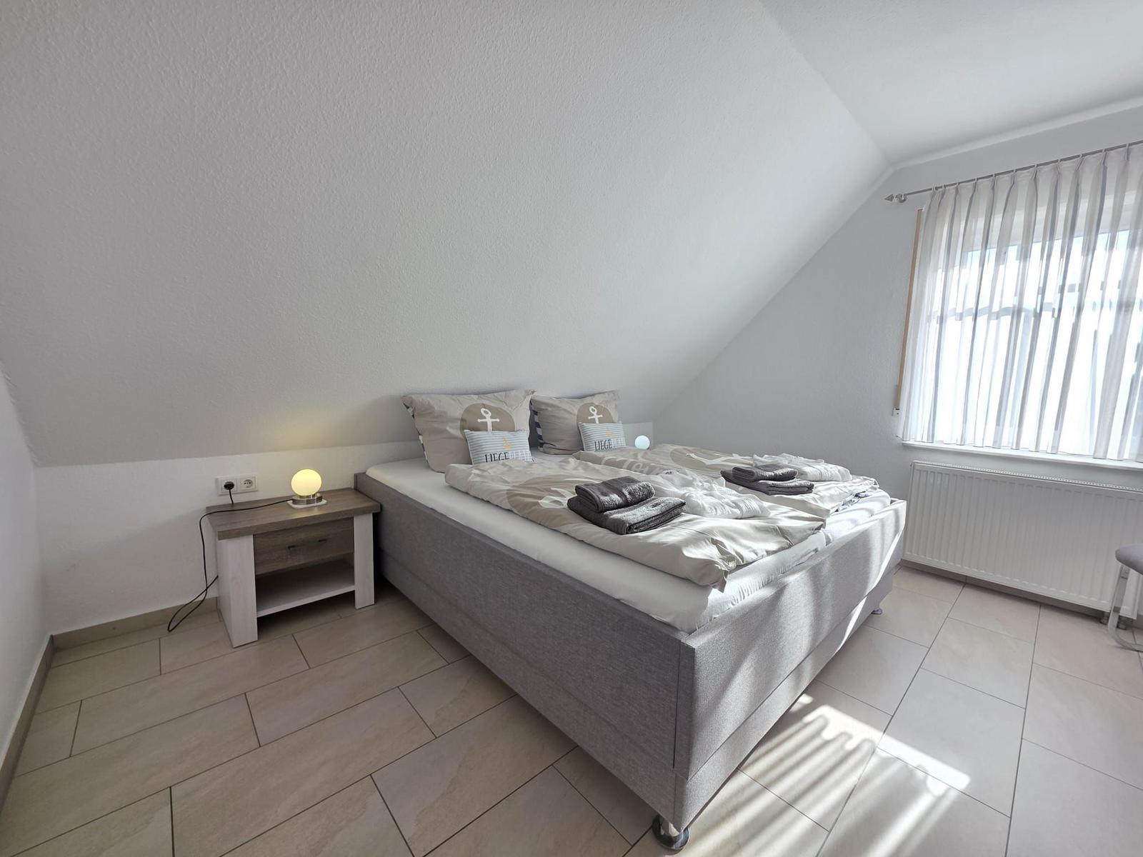 Bedroom with double bed, nightstand, and window with blinds.