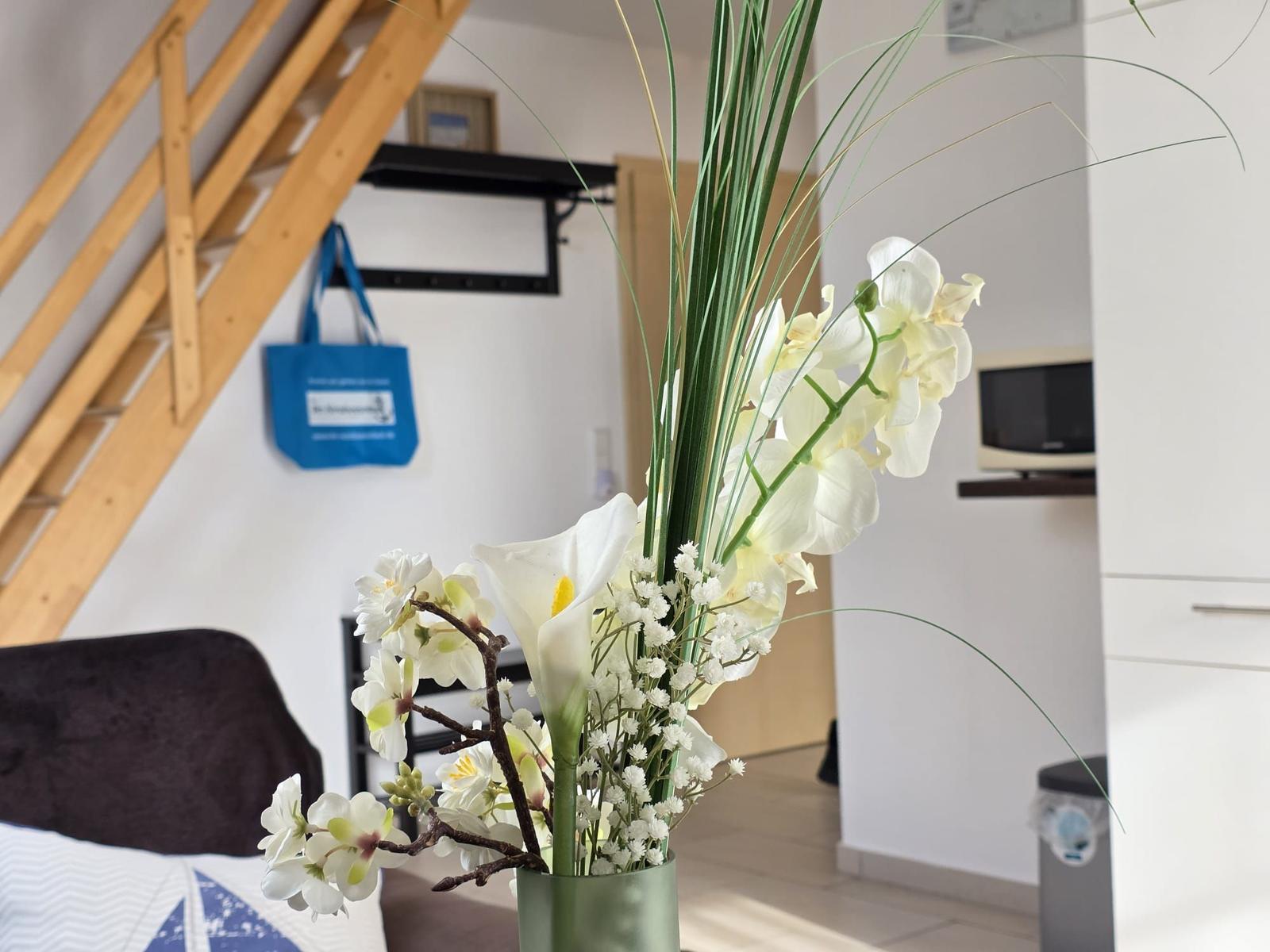 Flower arrangement in foreground, stairs and kitchen area behind.