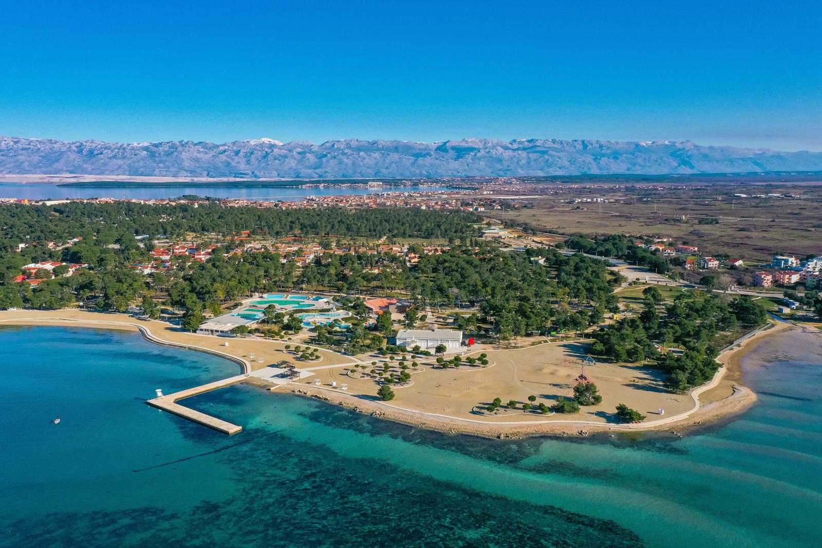 Aussicht auf Strand, Poolbereich und Berge am Meer