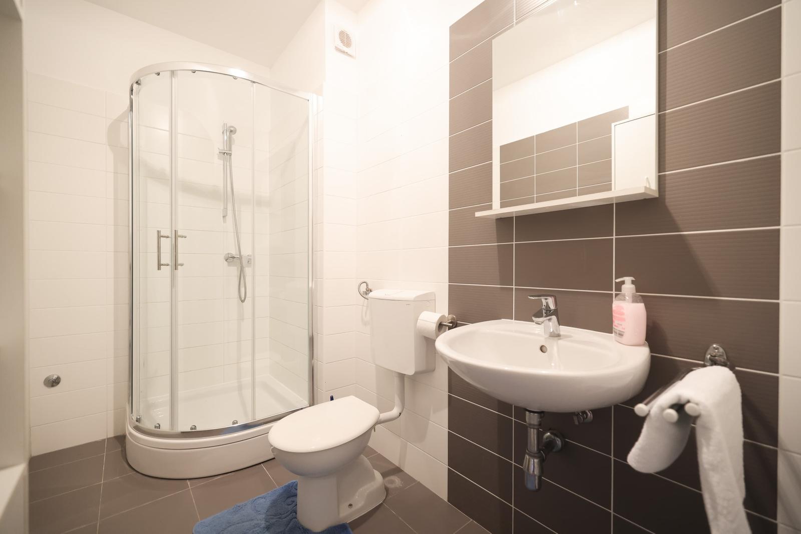 Badezimmer mit Dusche, Toilette und Waschbecken.