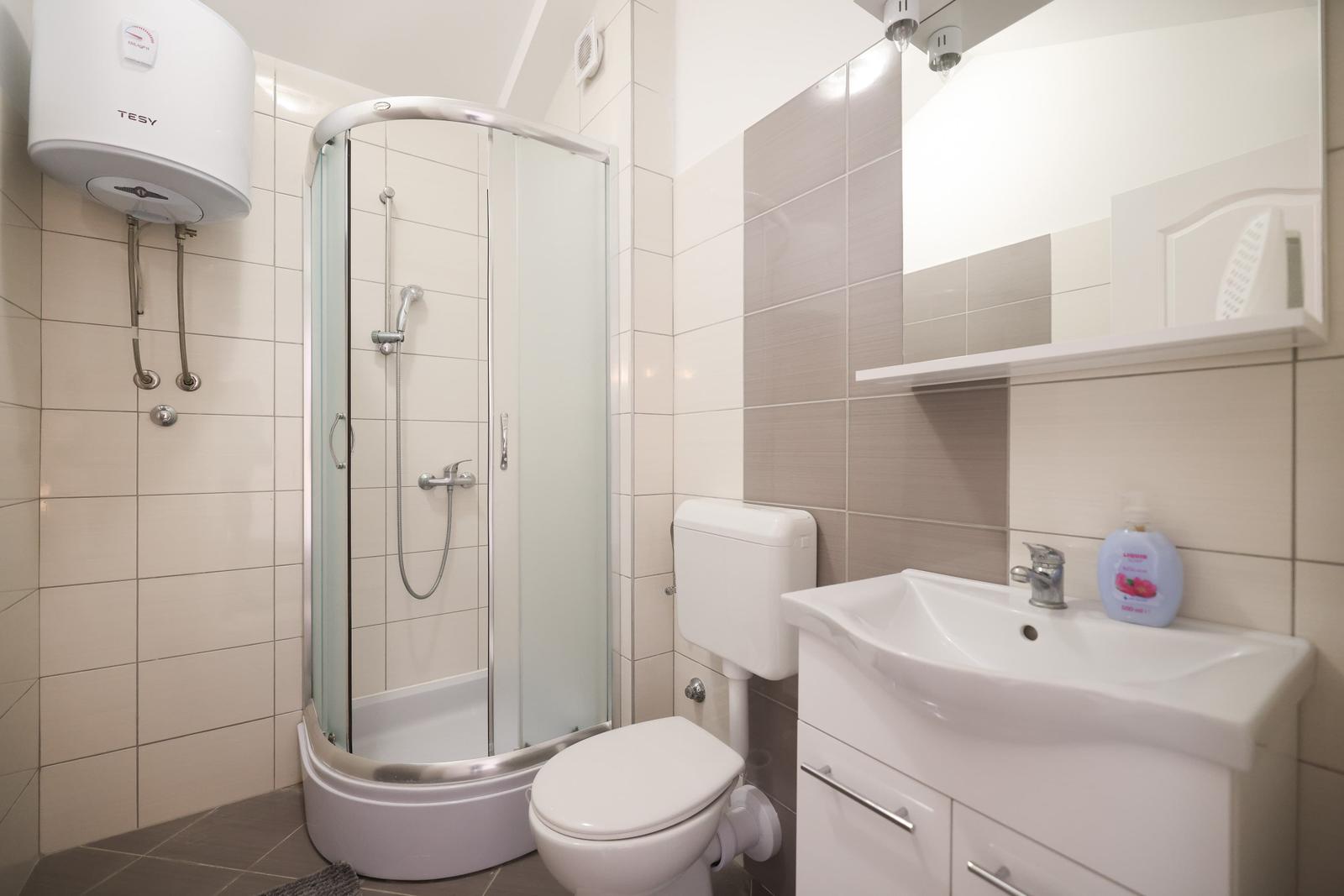 Badezimmer mit Dusche, Waschbecken und Toilette.