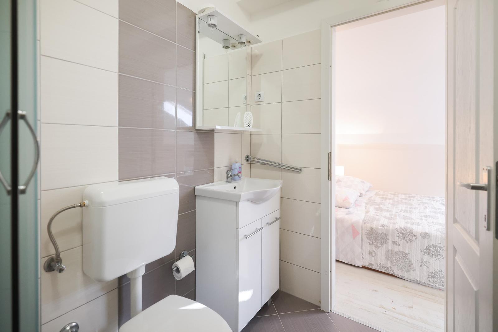 Badezimmer mit Toilette und Waschbecken. Durchgang zur Schlafzimmer.