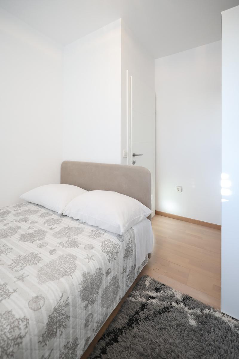 Schlafzimmer mit Bett, Teppich und Holzboden. Tür und Wand sind weiß.