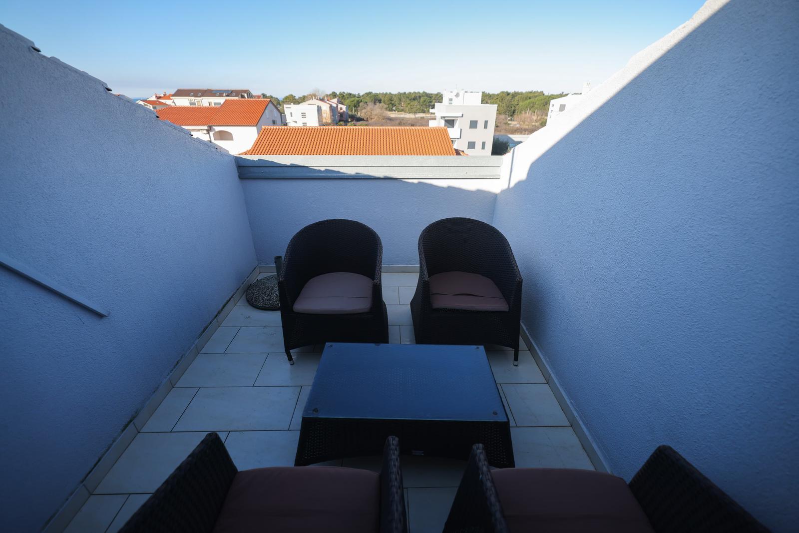 Terrasse mit vier Sitzgelegenheiten und Blick auf Dächer.