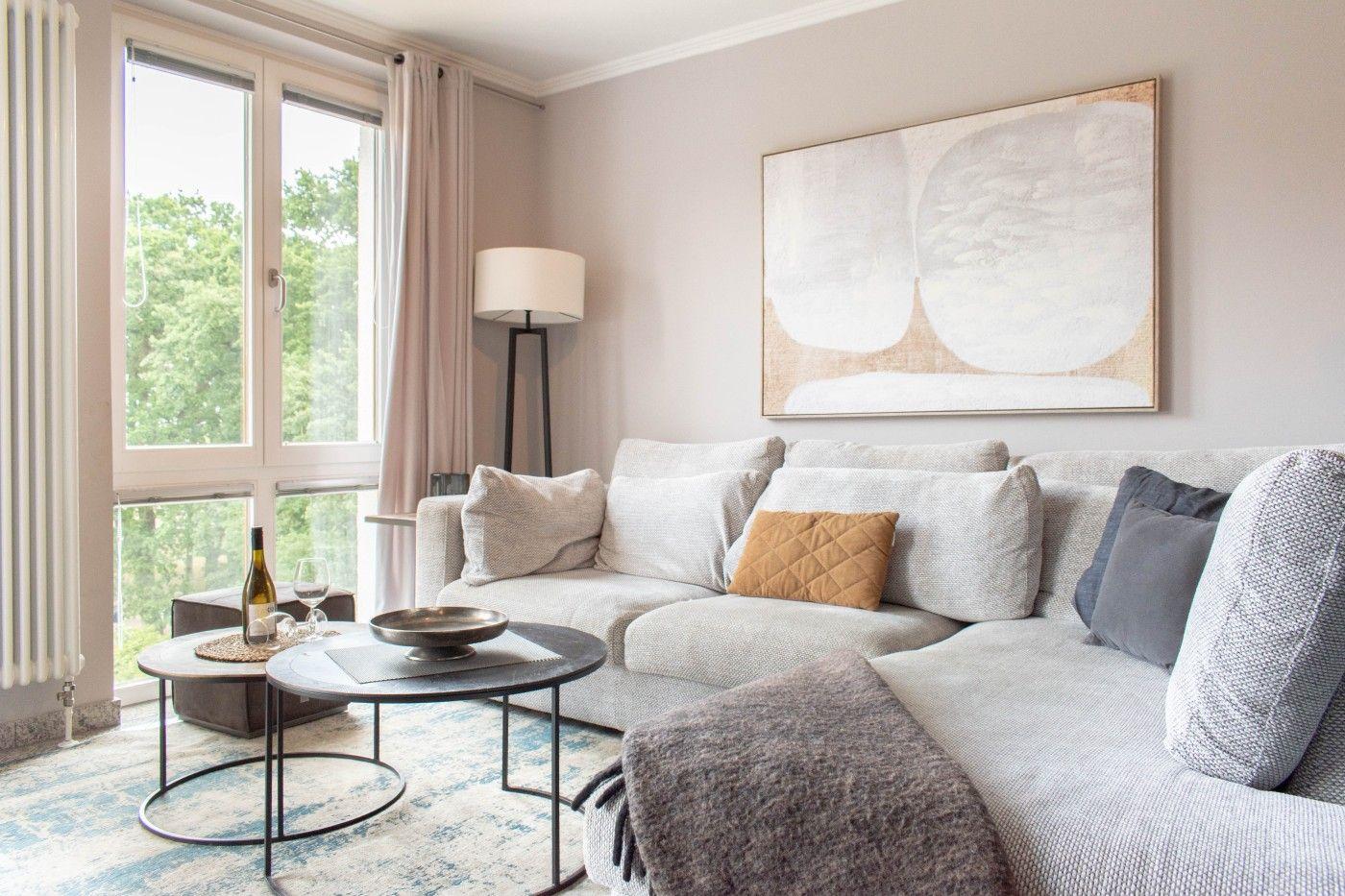 Wohnzimmer mit Sofa, Tisch und Fenster mit Blick auf Grün.