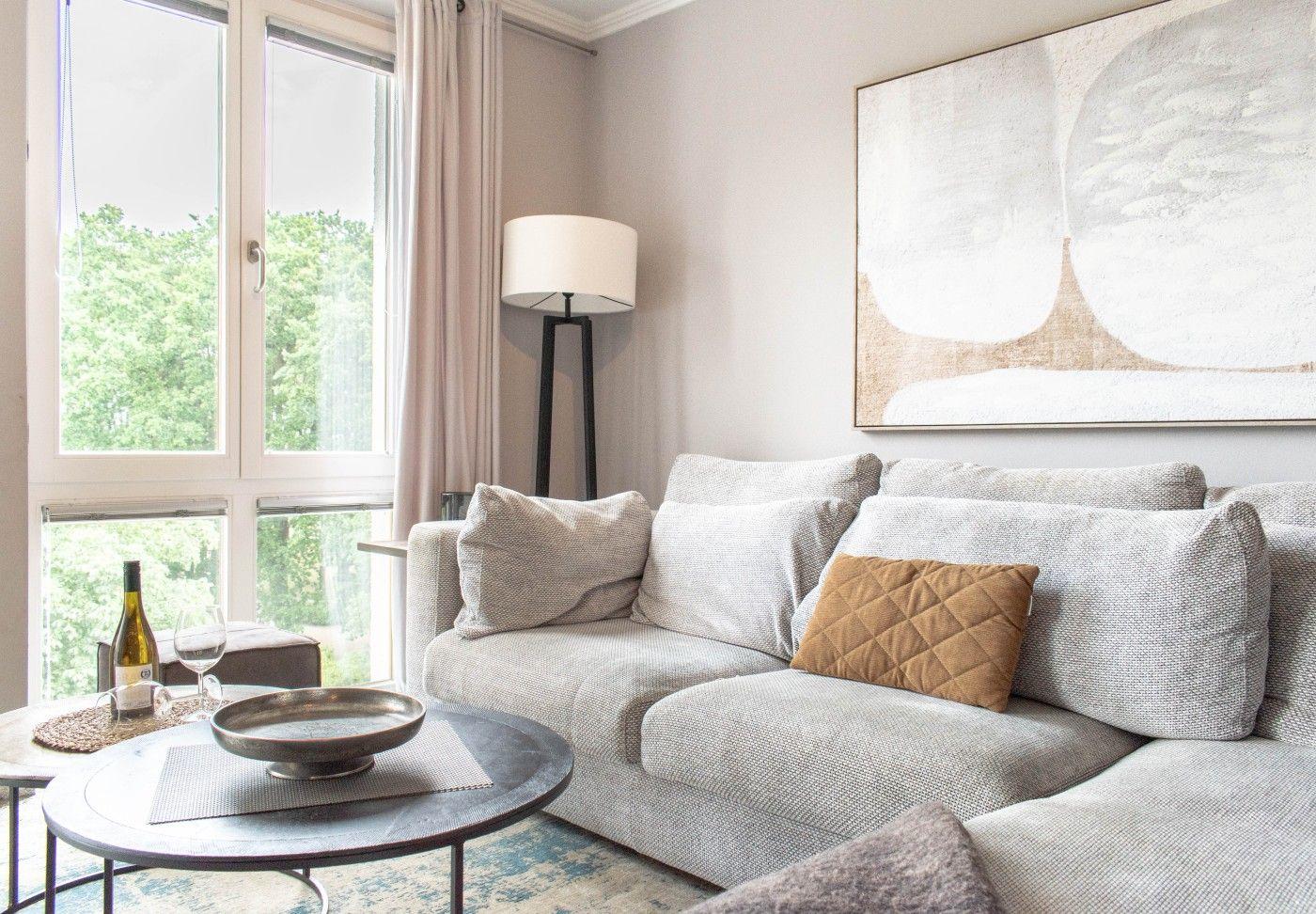 Ein Wohnzimmer mit Sofa, Tisch und Fensterblick auf Bäume.