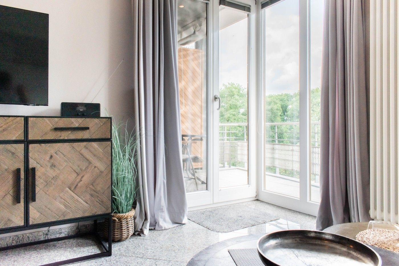 Wohnzimmer mit TV, Schrank und Balkonansicht.