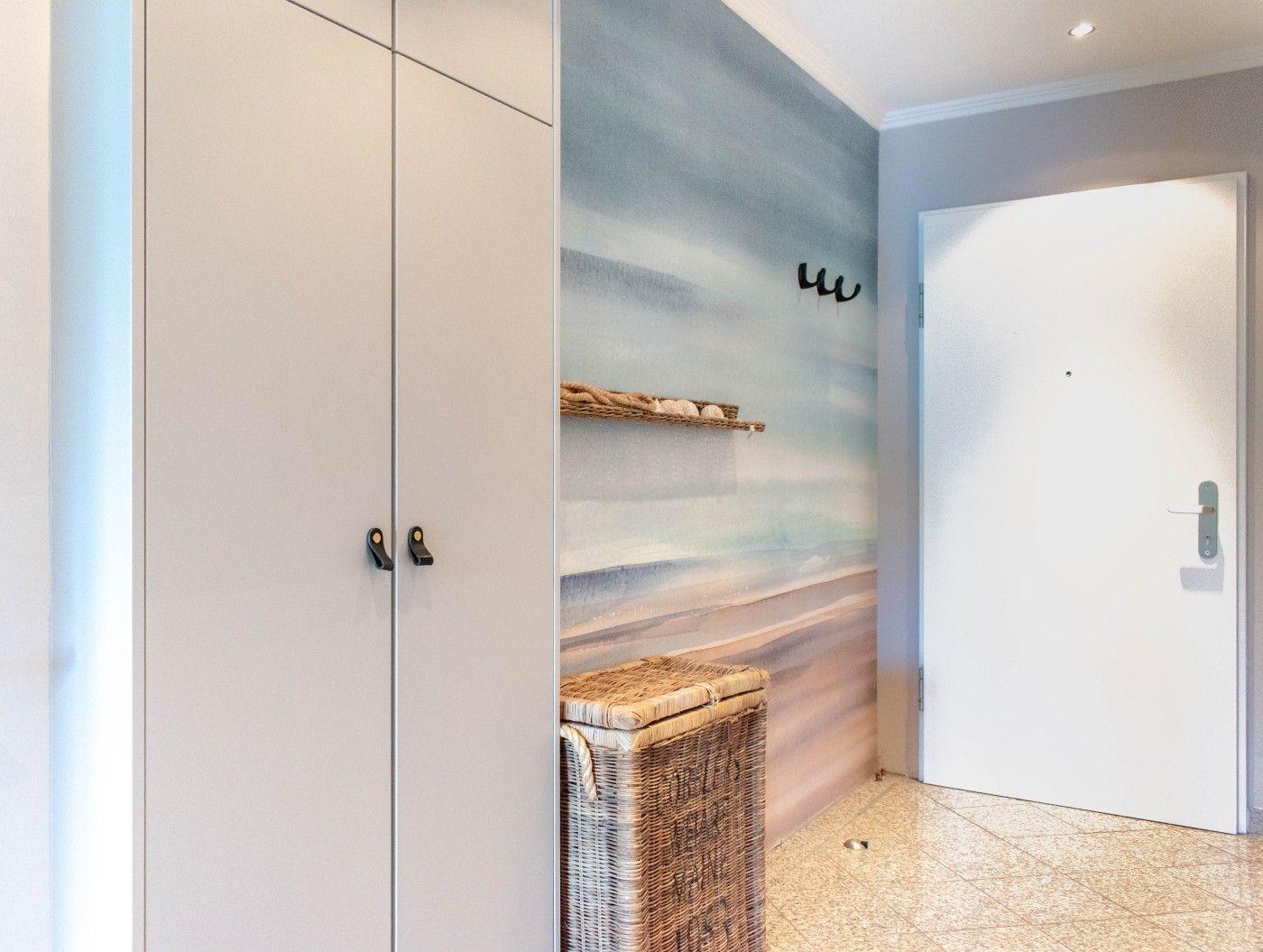 Eingangsbereich mit Garderobe, Wandbild und Korb.