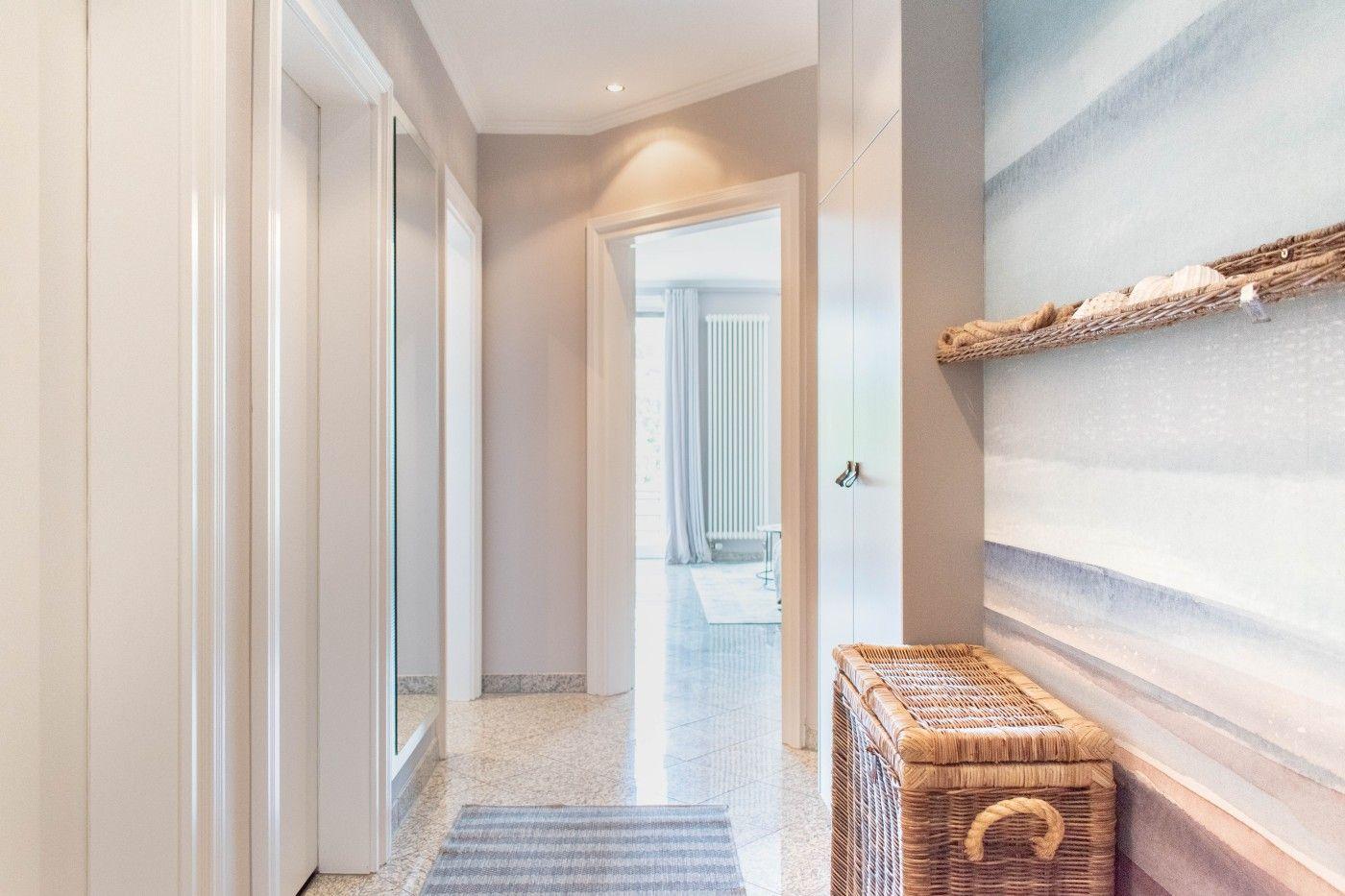 Flur mit Wickerkorb und Wandbild, Tür zu Wohnzimmer sichtbar.