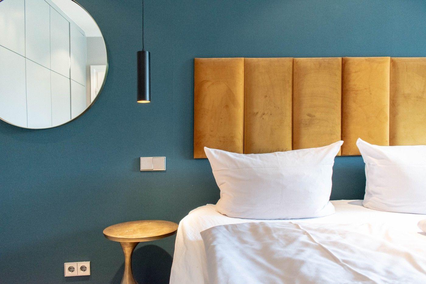 Schlafzimmer mit Bett, Kopfteil und Wandspiegel