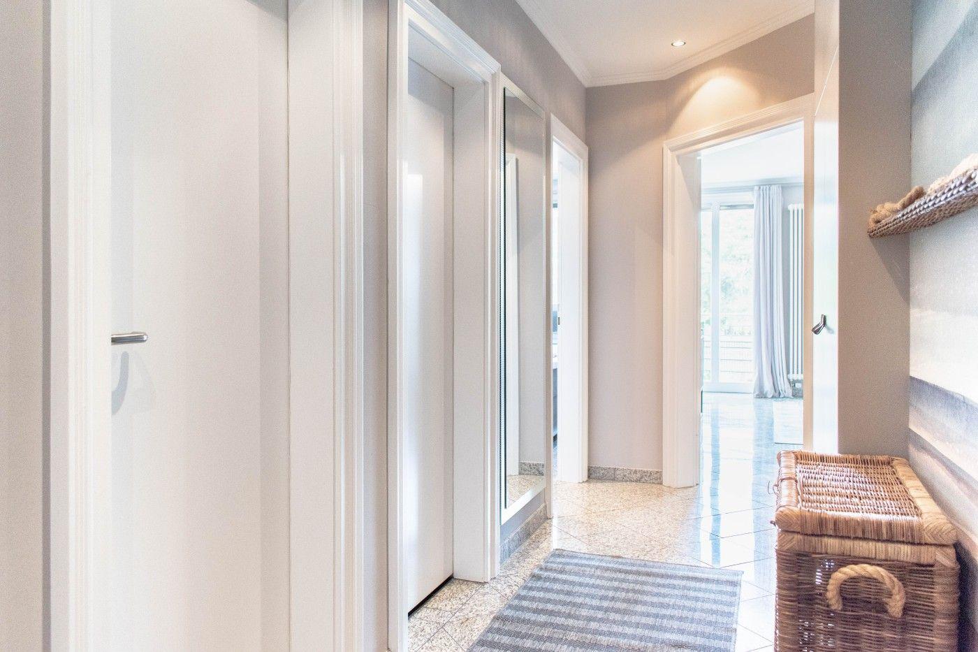 Flur mit Türen, Teppich und Korb. Durchgang zu Wohnbereich mit Balkontür.