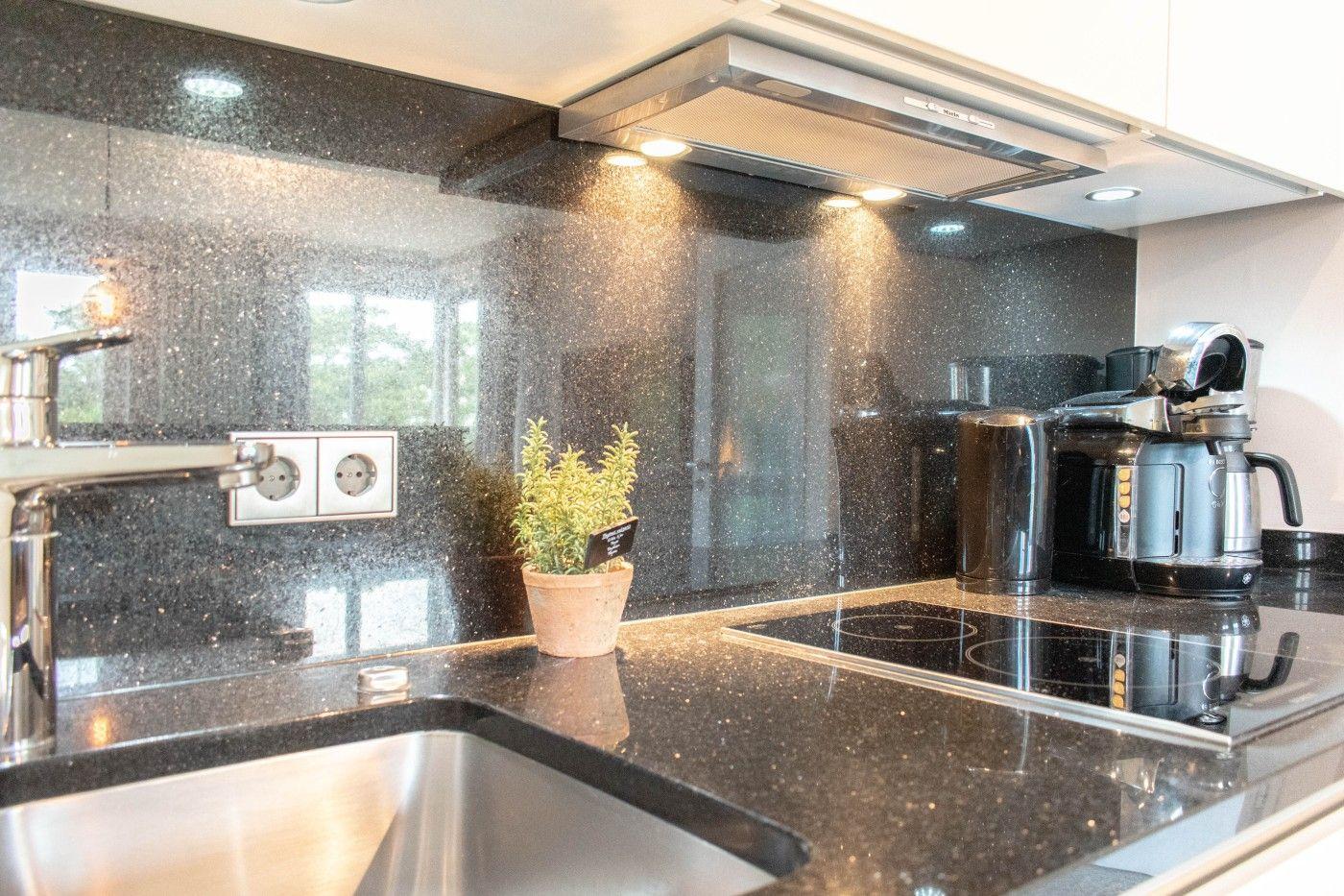 Küche mit schwarzer Arbeitsplatte, Edelstahlspüle und Kaffeemaschine.