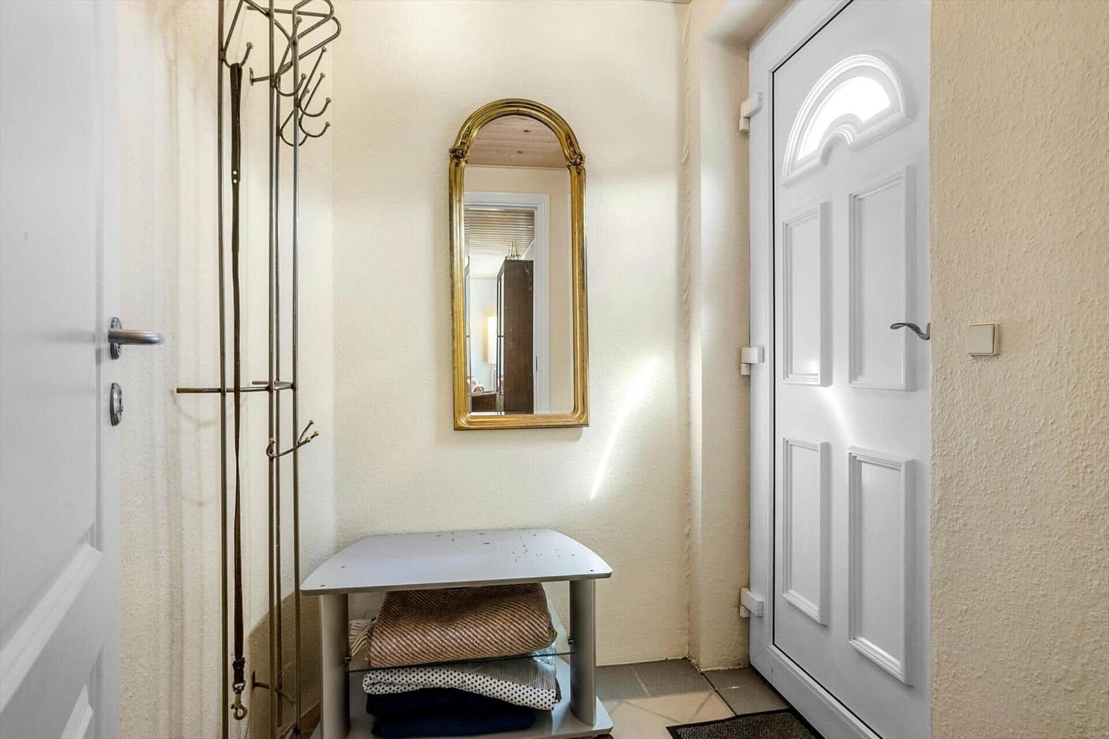 Entrance area with mirror, coat rack, and bench with blankets.