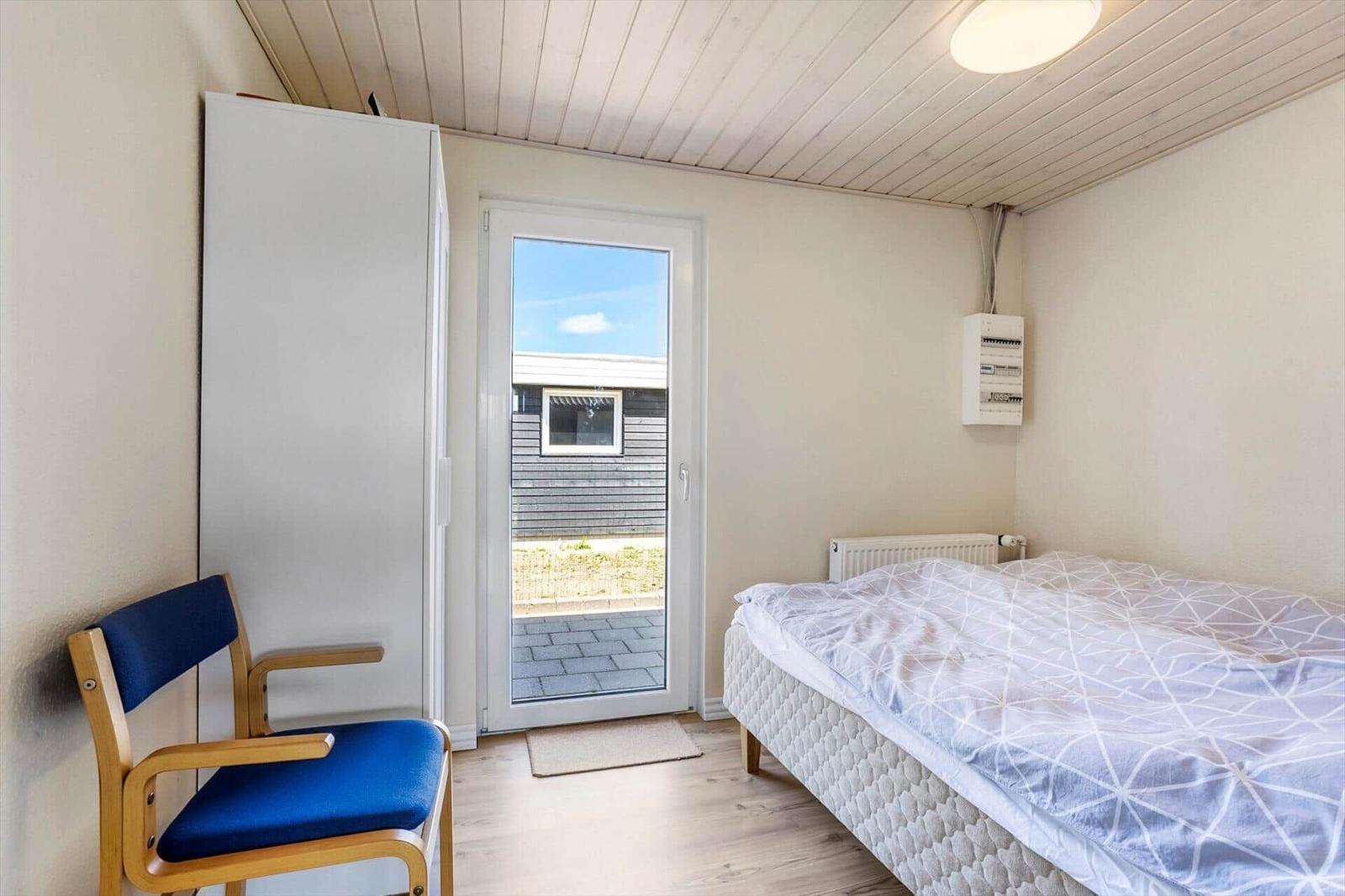 Bedroom with bed, chair, and door to outdoor area.