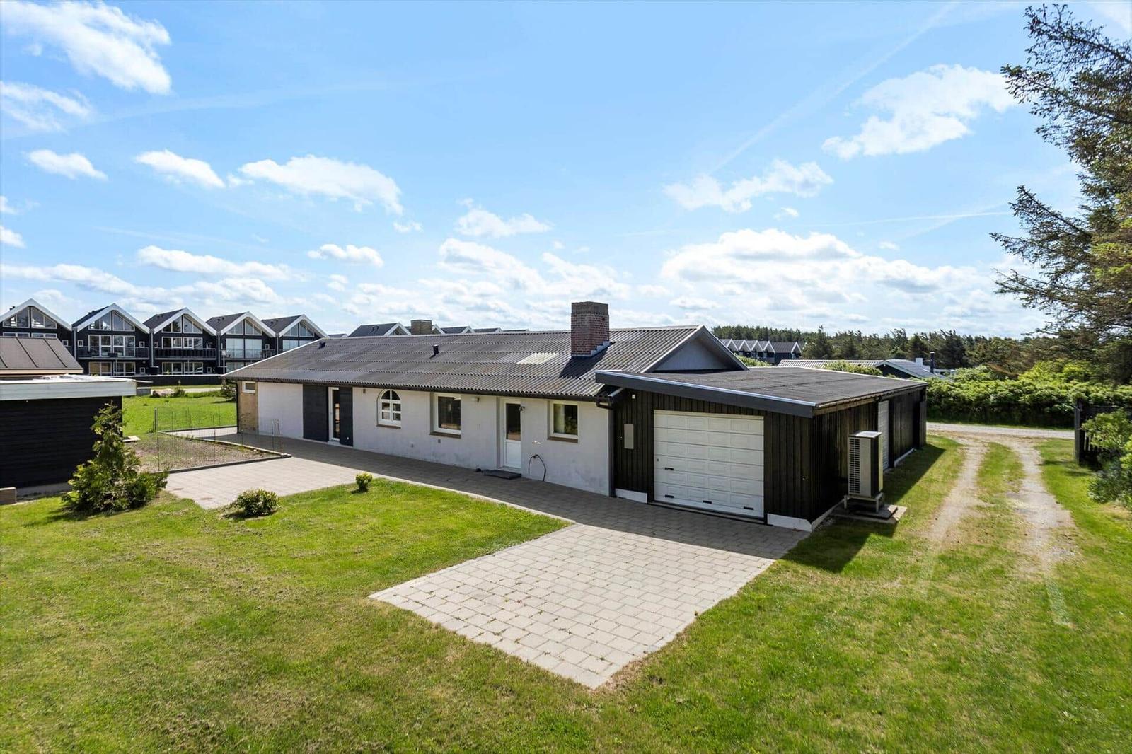 Single-family house with garage and garden. Backyard with forest and clear sky.