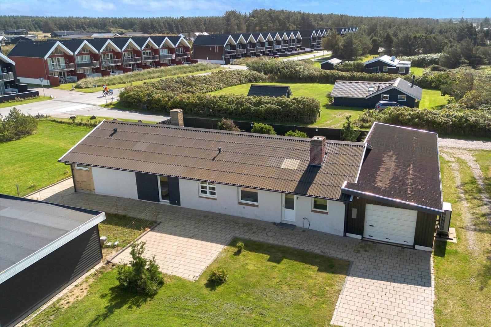 Single-family house with garage and garden. Several houses and trees are visible in the background.