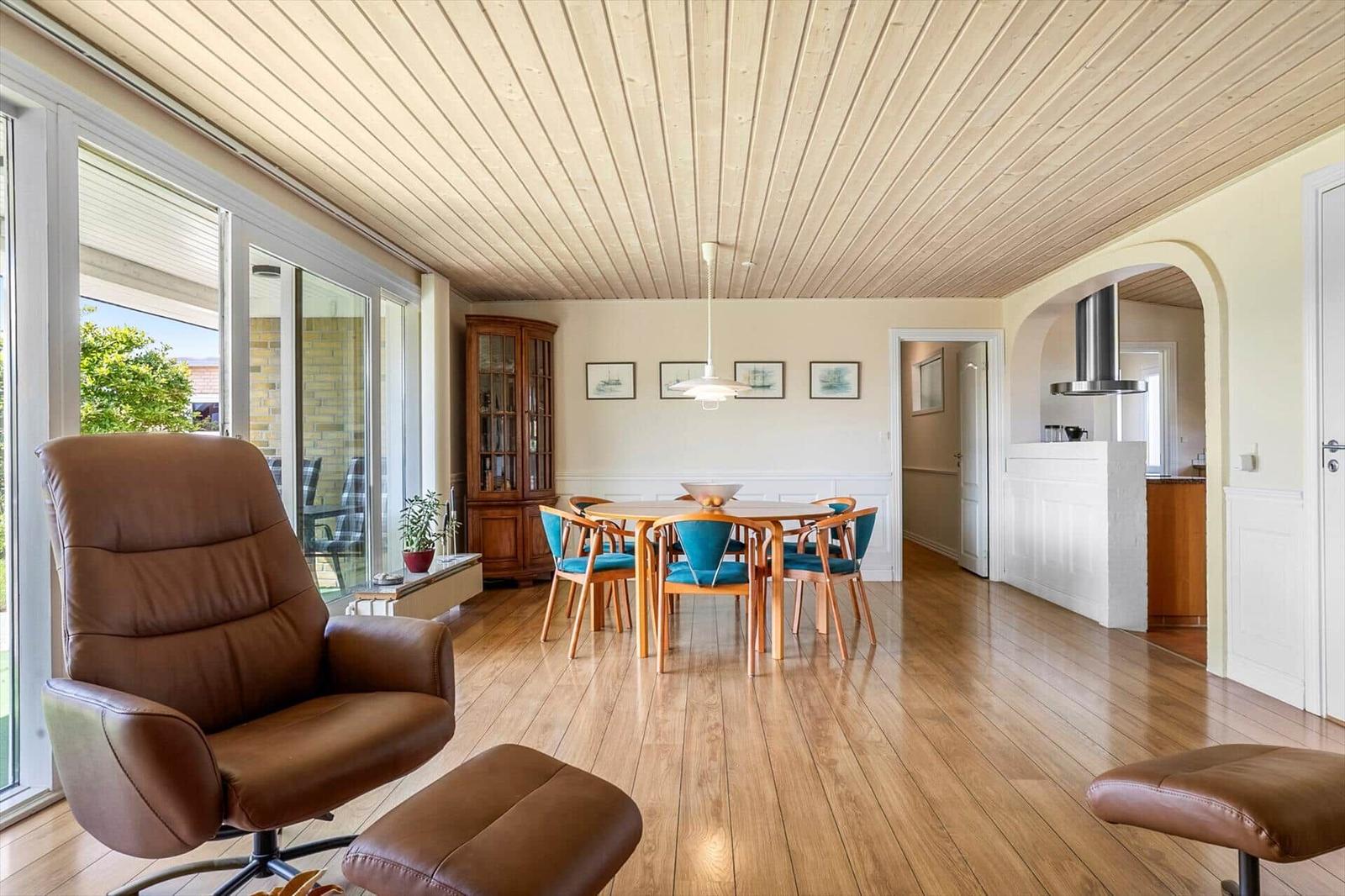 Living and dining area with wooden floor, dining table, and brown armchair.
