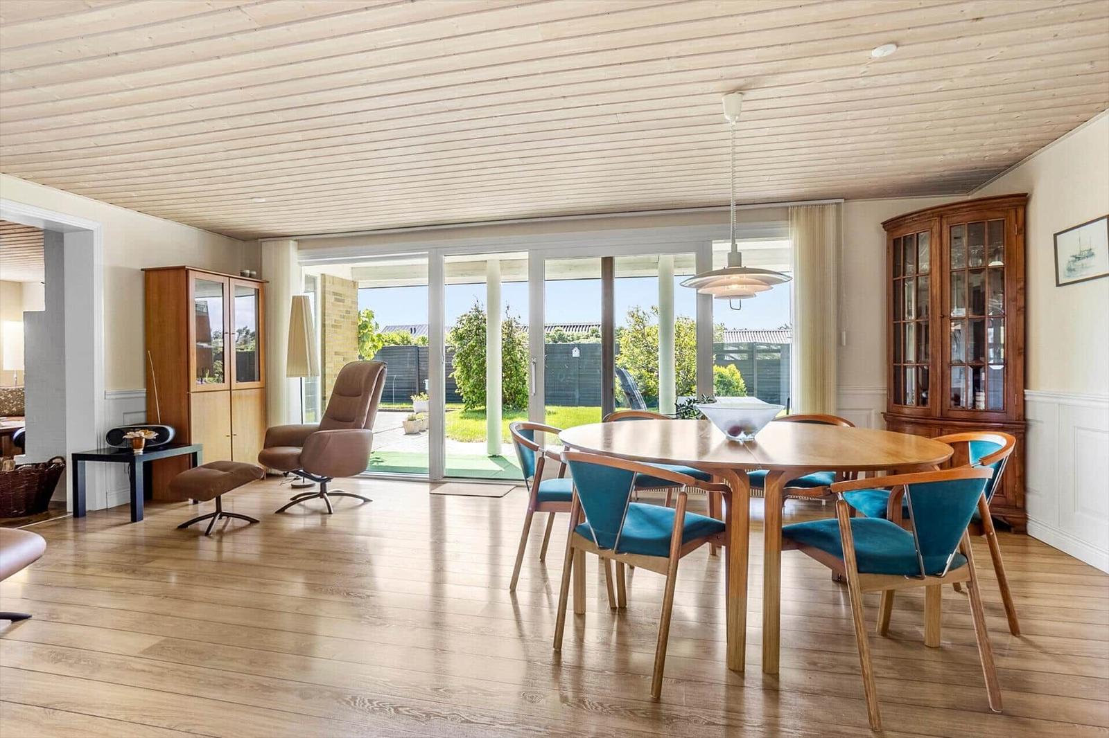 Dining room with wooden table, blue chairs, and glass doors to the garden.