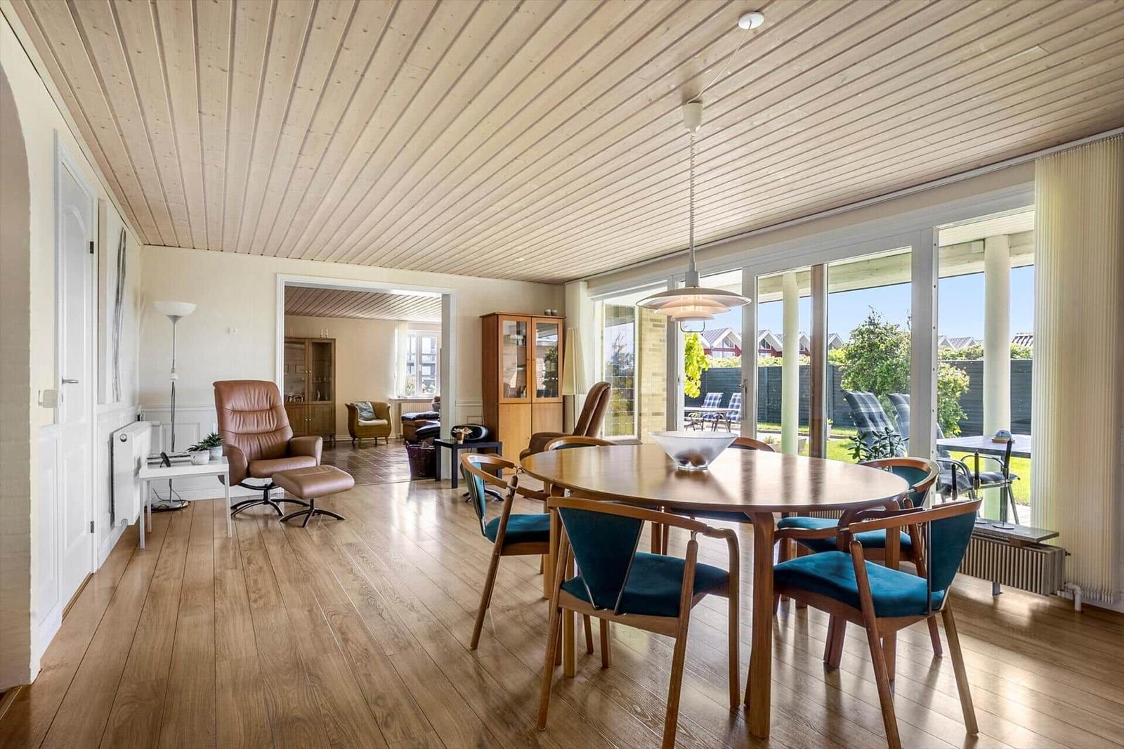 Dining room with wooden table and blue chairs, view of garden.