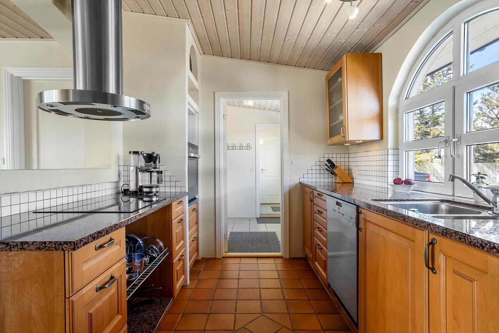 Kitchen with wooden cabinets, stainless steel sink and terracotta floor
