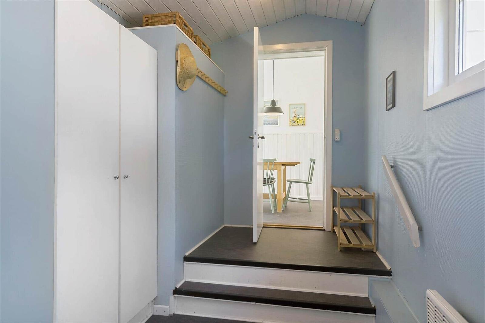 Entrance with closet, steps, and view into dining room.