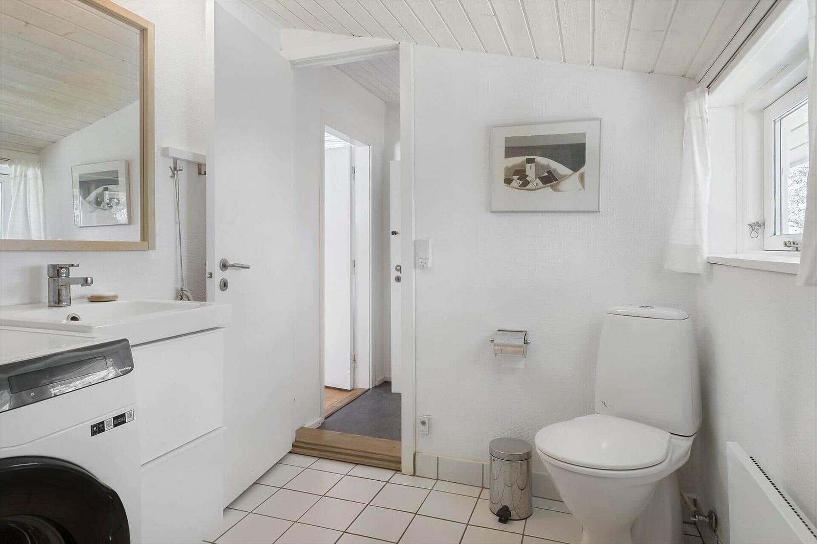 Bathroom with toilet, sink, and mirror. Window and door visible.