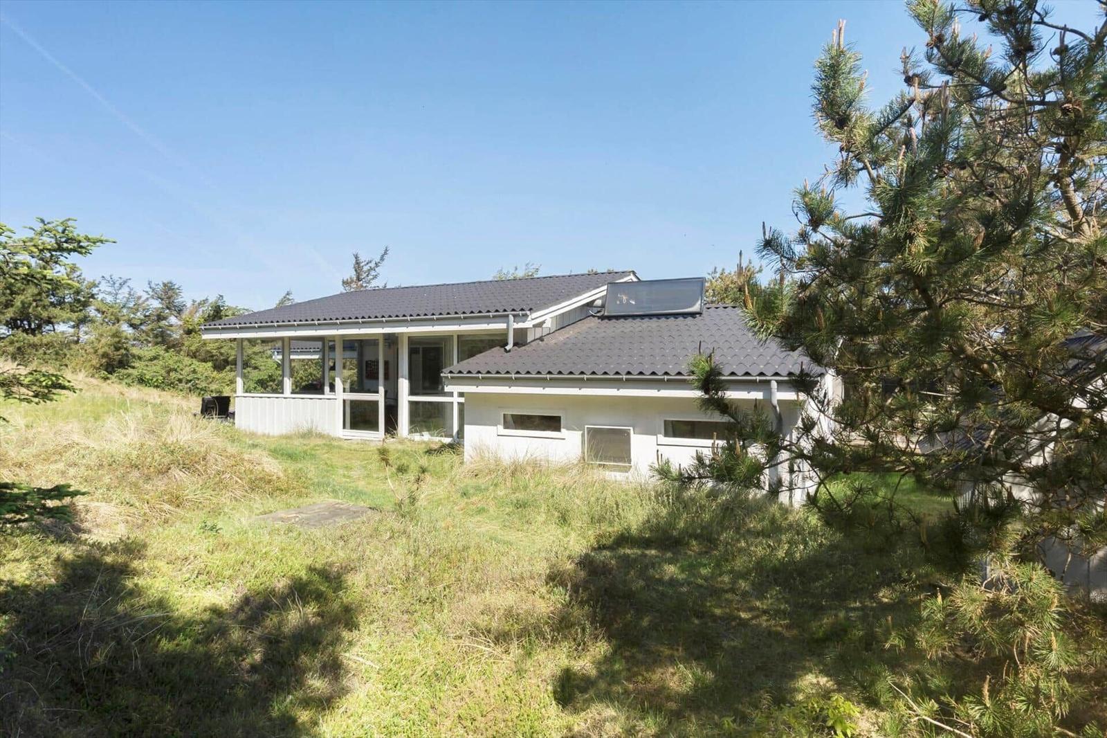 House with terrace and solar panels on grassy lawn.