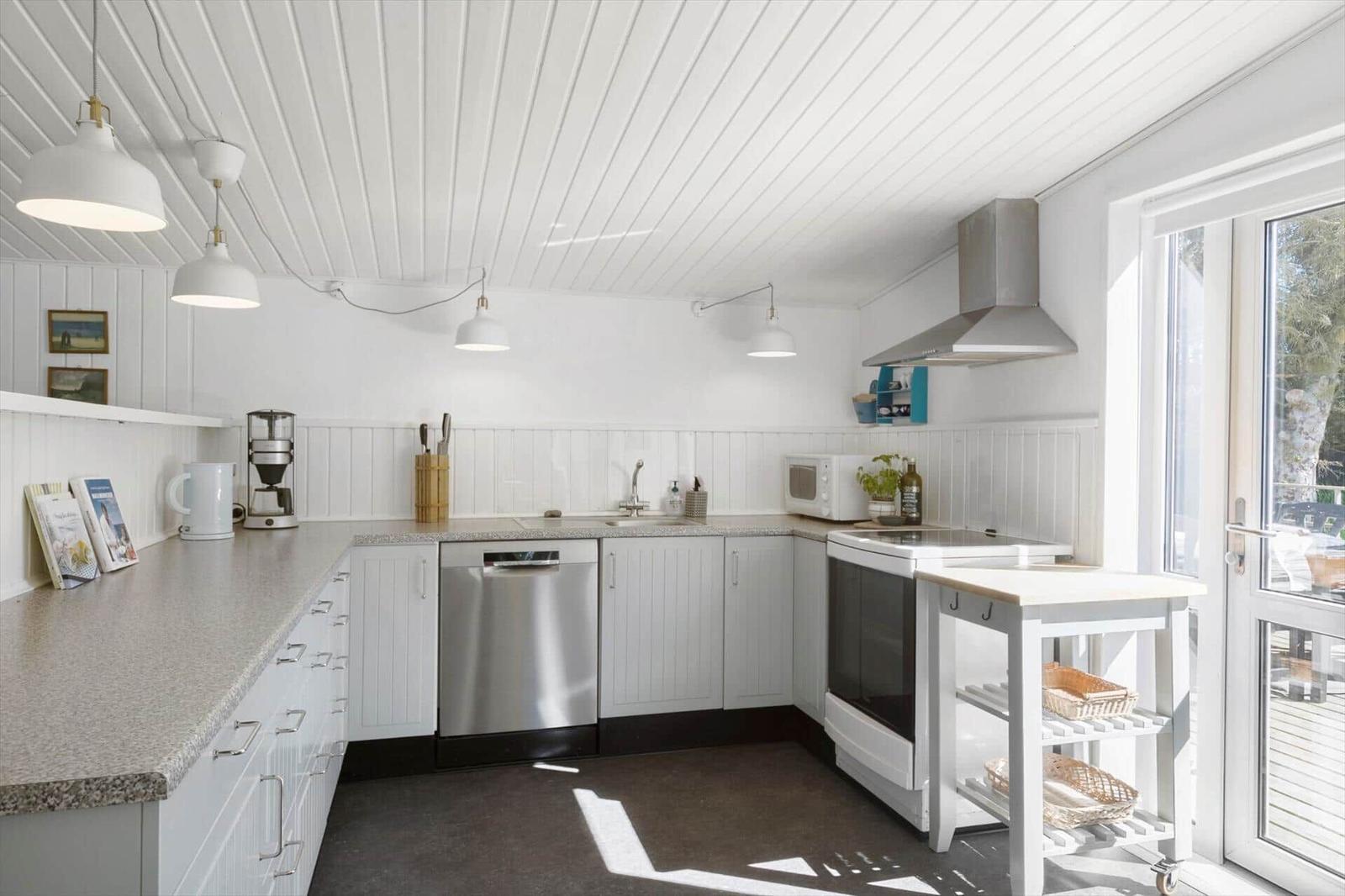 Kitchen with white cabinets, stainless steel sink, and window to terrace.