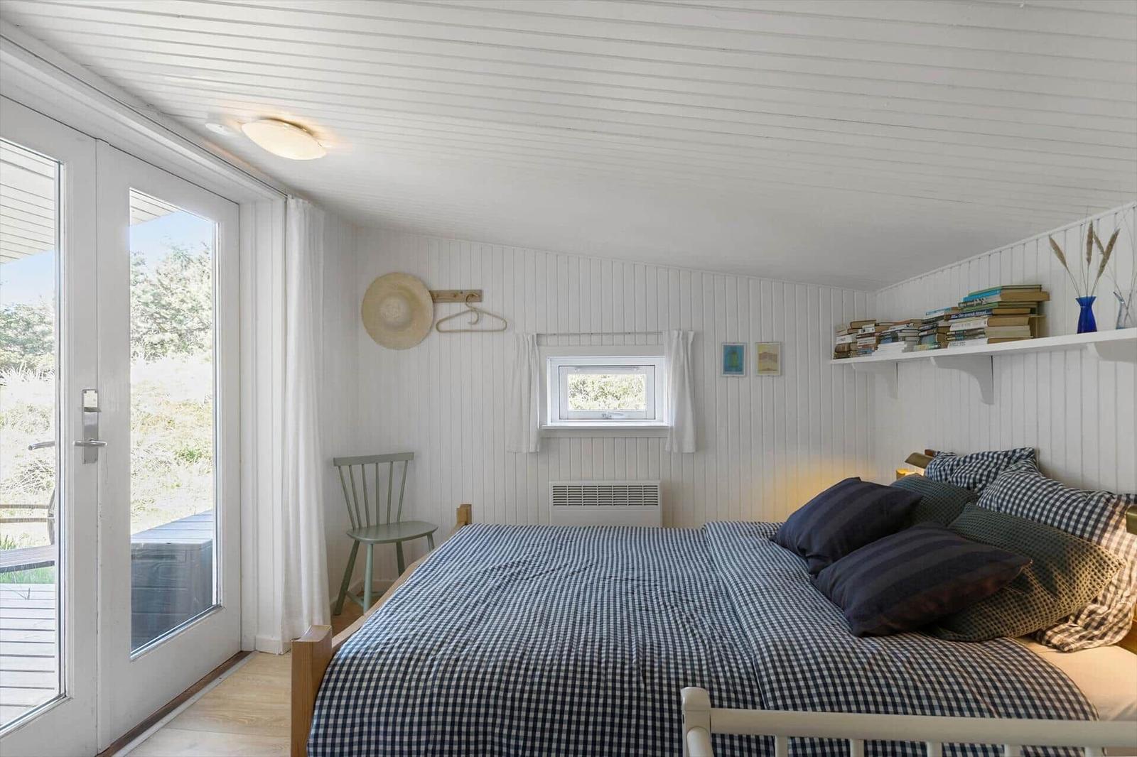 Bedroom with bed, window, and door to balcony.