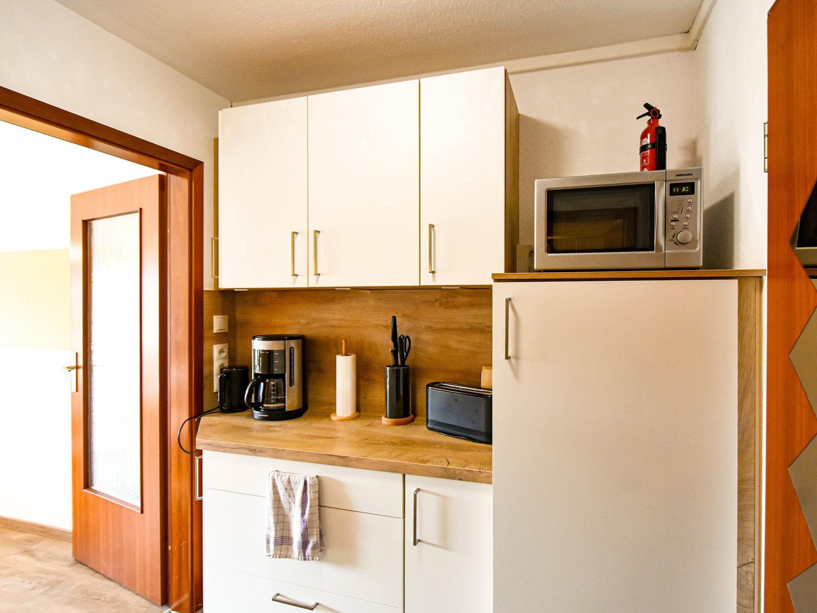 Küche mit Kühlschrank, Mikrowelle und Kaffeemaschine.