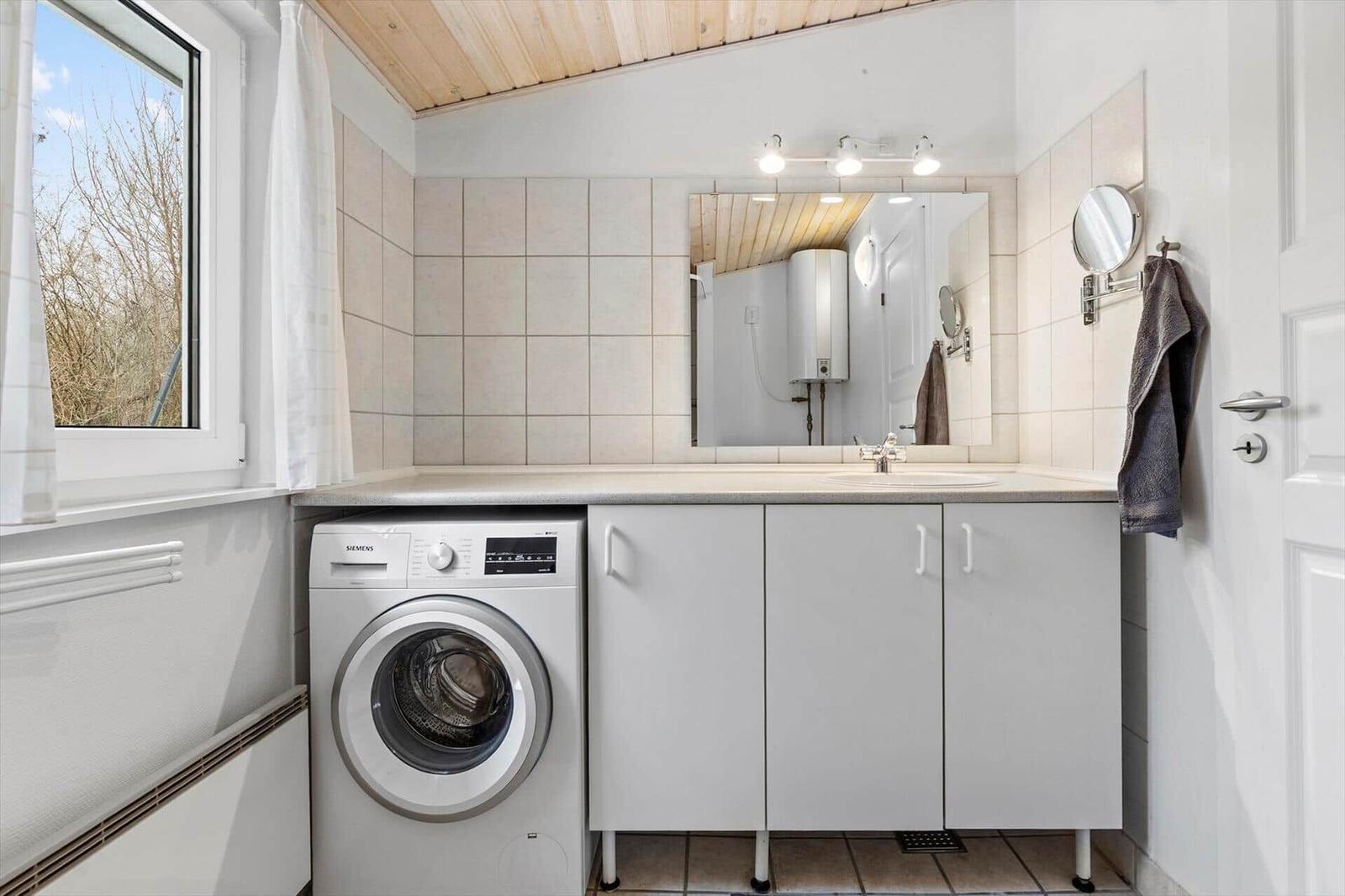 Bathroom with washing machine, mirror, and window.