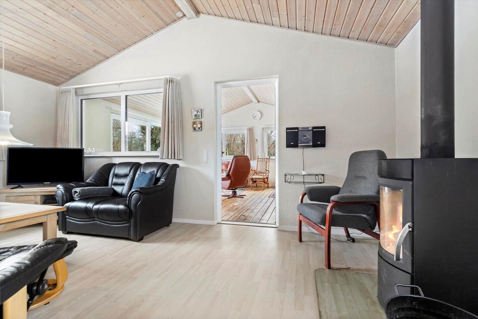 Living room with fireplace, leather sofa, and view into the kitchen.