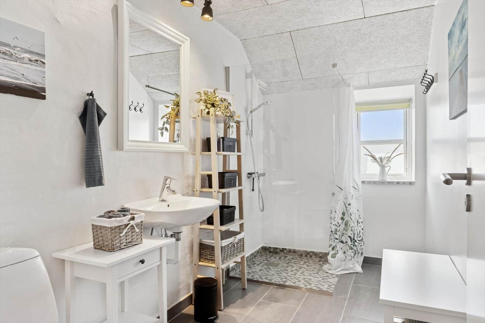 Badezimmer mit Dusche, Waschbecken und Fenster.