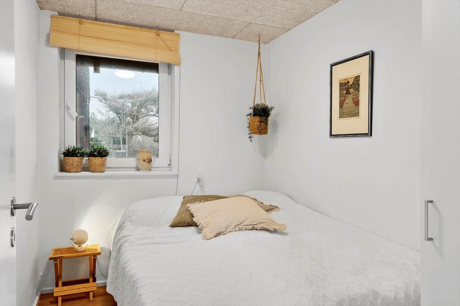 Ein Schlafzimmer mit Bett, Fenster und Pflanzen.