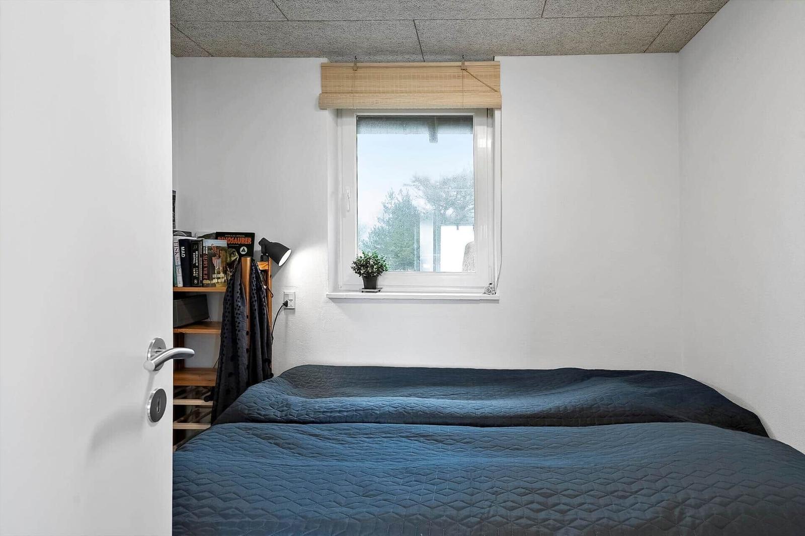 Schlafzimmer mit Bett, Fenster und Bücherregal.
