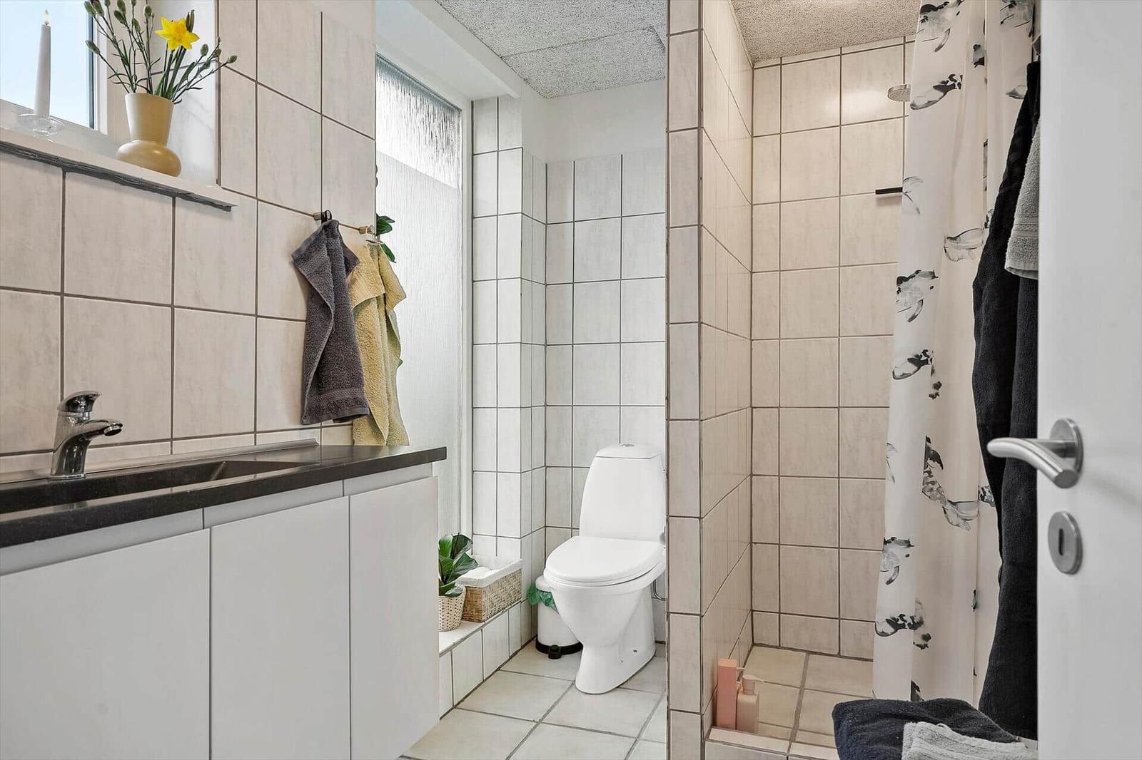 Badezimmer mit Waschbecken, Toilette und Dusche mit Vorhang.
