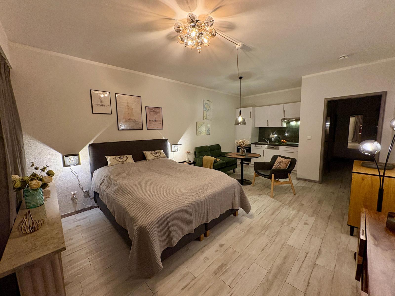 Schlafzimmer mit Bett, Wohnbereich und Küche im offenen Raum.