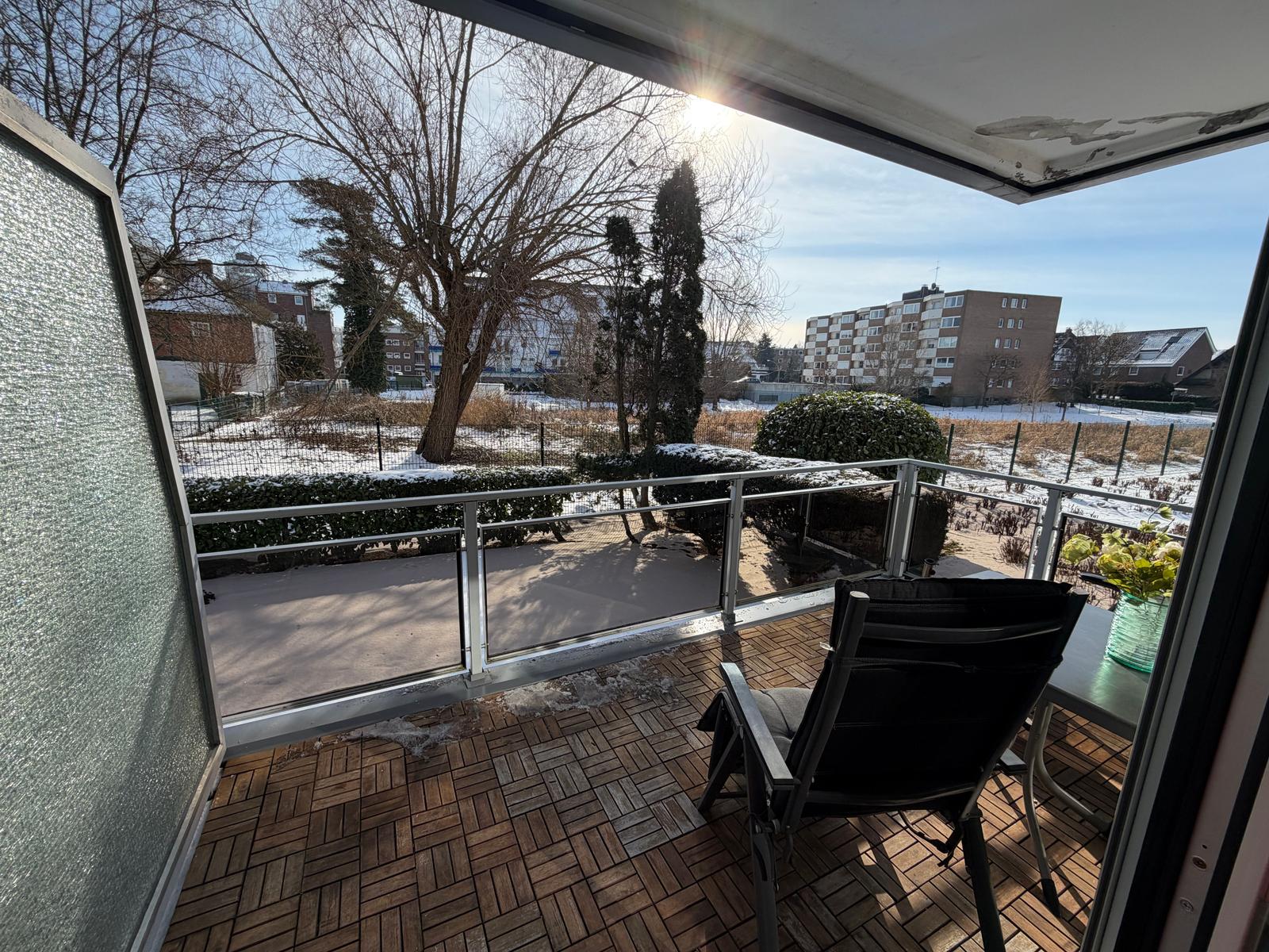 Terrasse mit Sitzgelegenheit und Blick auf schneebedeckten Garten und Wohnhäuser.