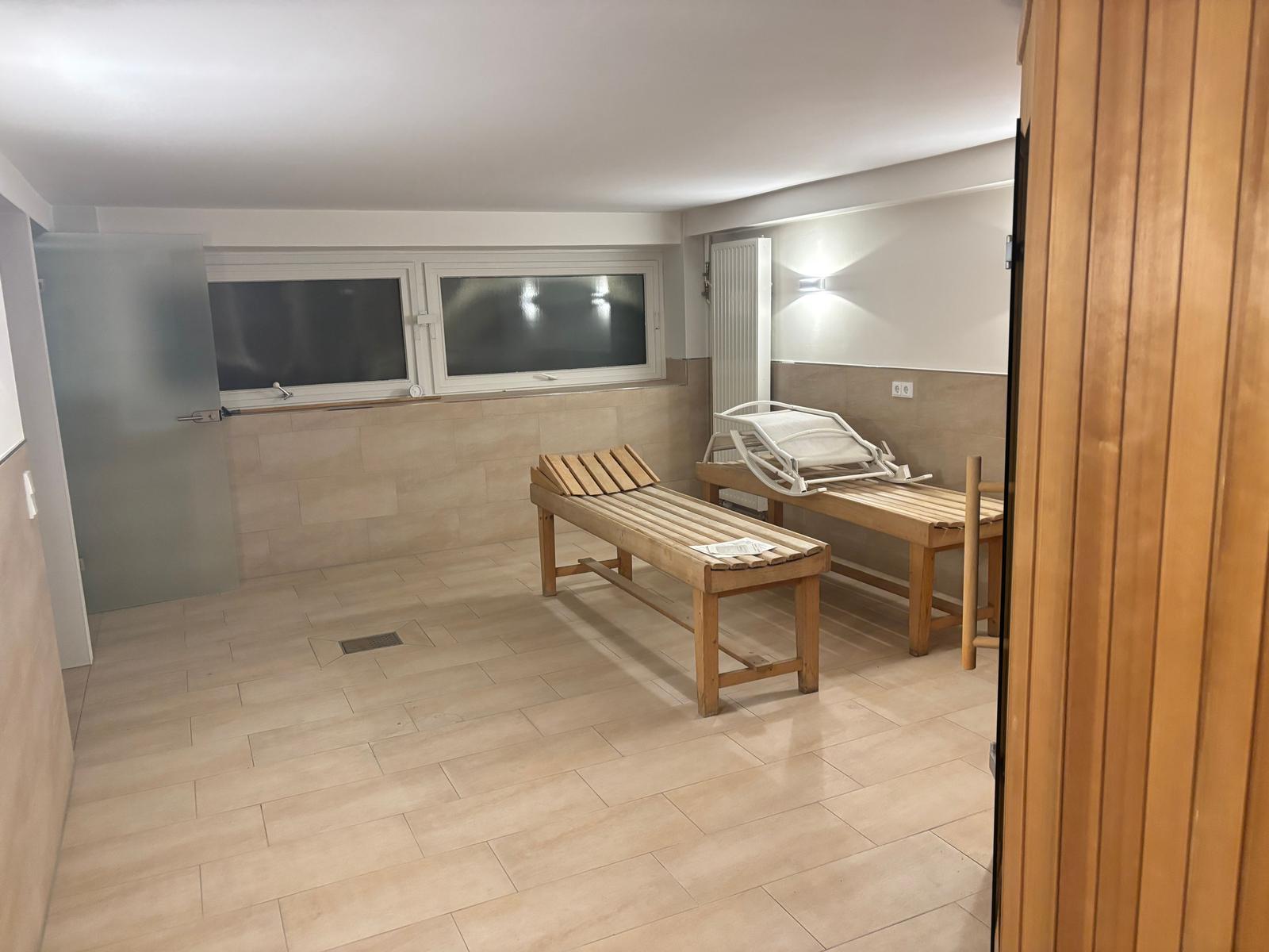 Sauna mit Holzliegen und Fenstern. Boden und Wände sind gefliest.