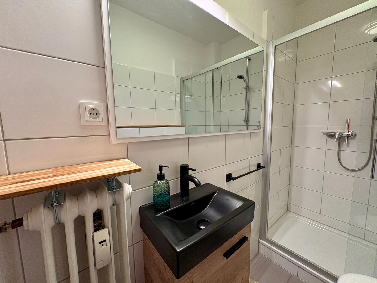 Badezimmer mit Dusche, Waschbecken und Spiegel