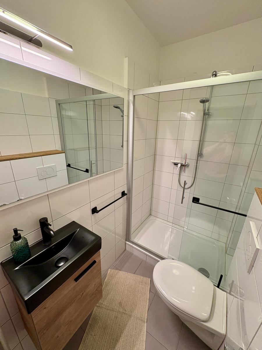 Badezimmer mit Dusche, Toilette und Waschbecken.