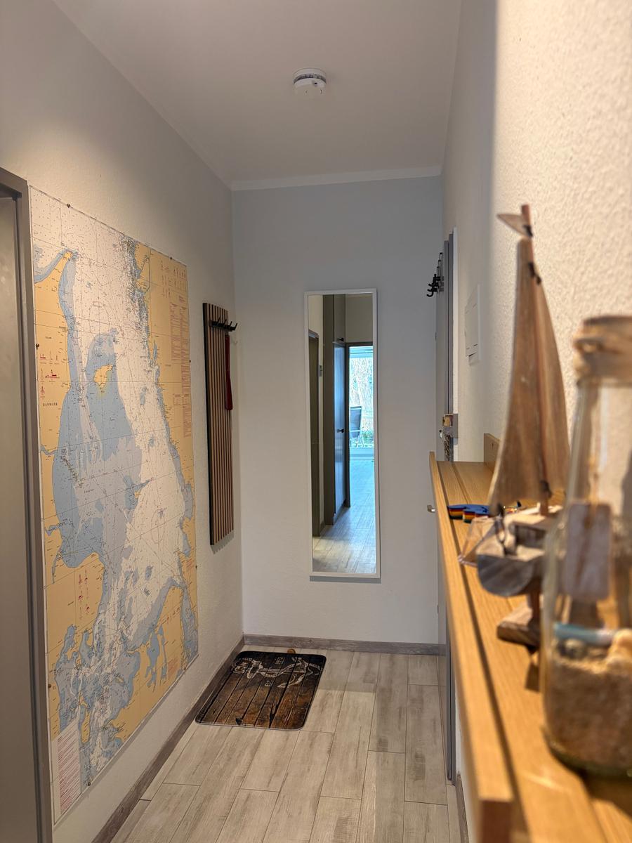 Flur mit Seekartenwand, Spiegel und Holzbank mit Segelmodell.